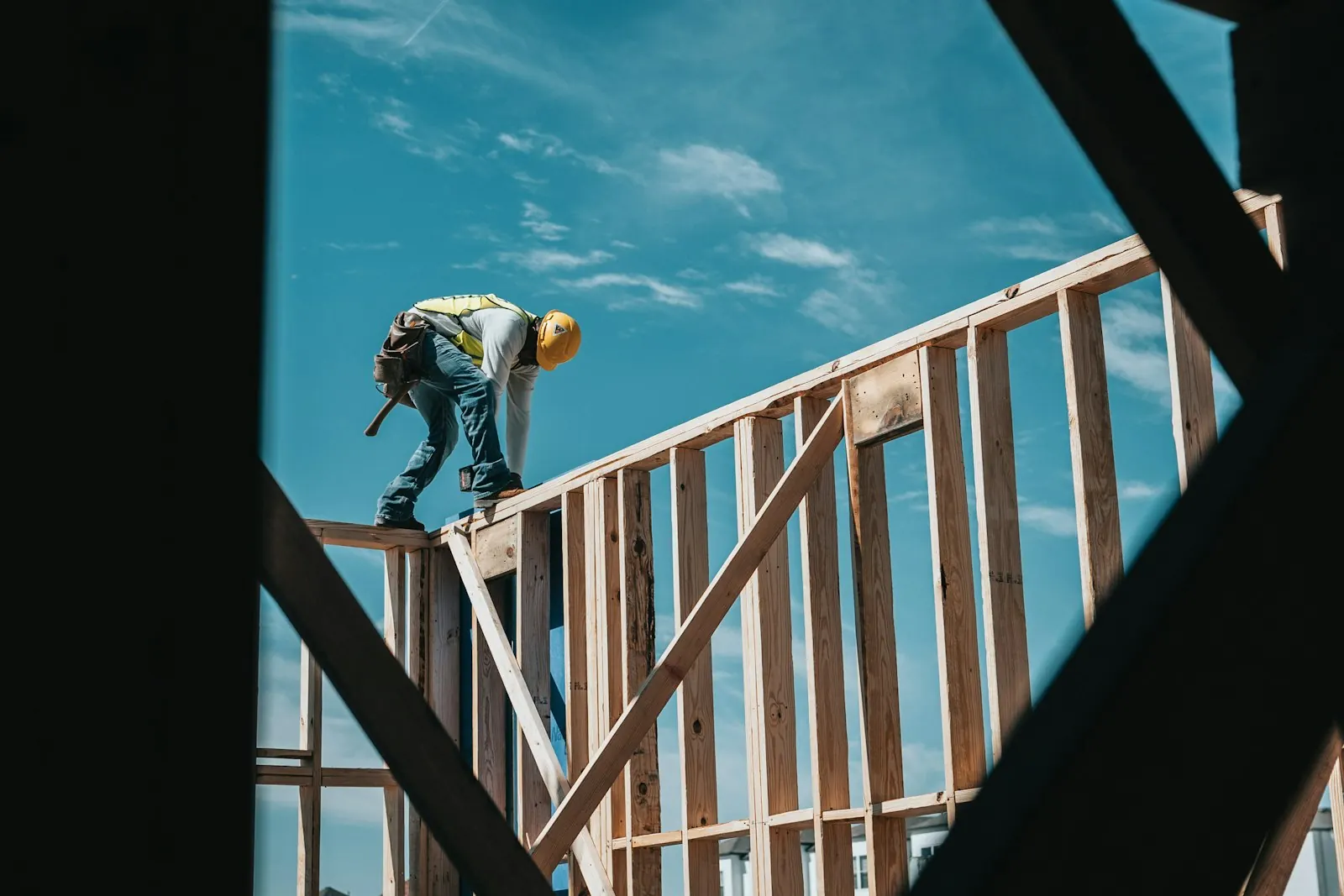Zimmerer mit Schutzhelm auf einem Holzständerwerk bei der Sanierung