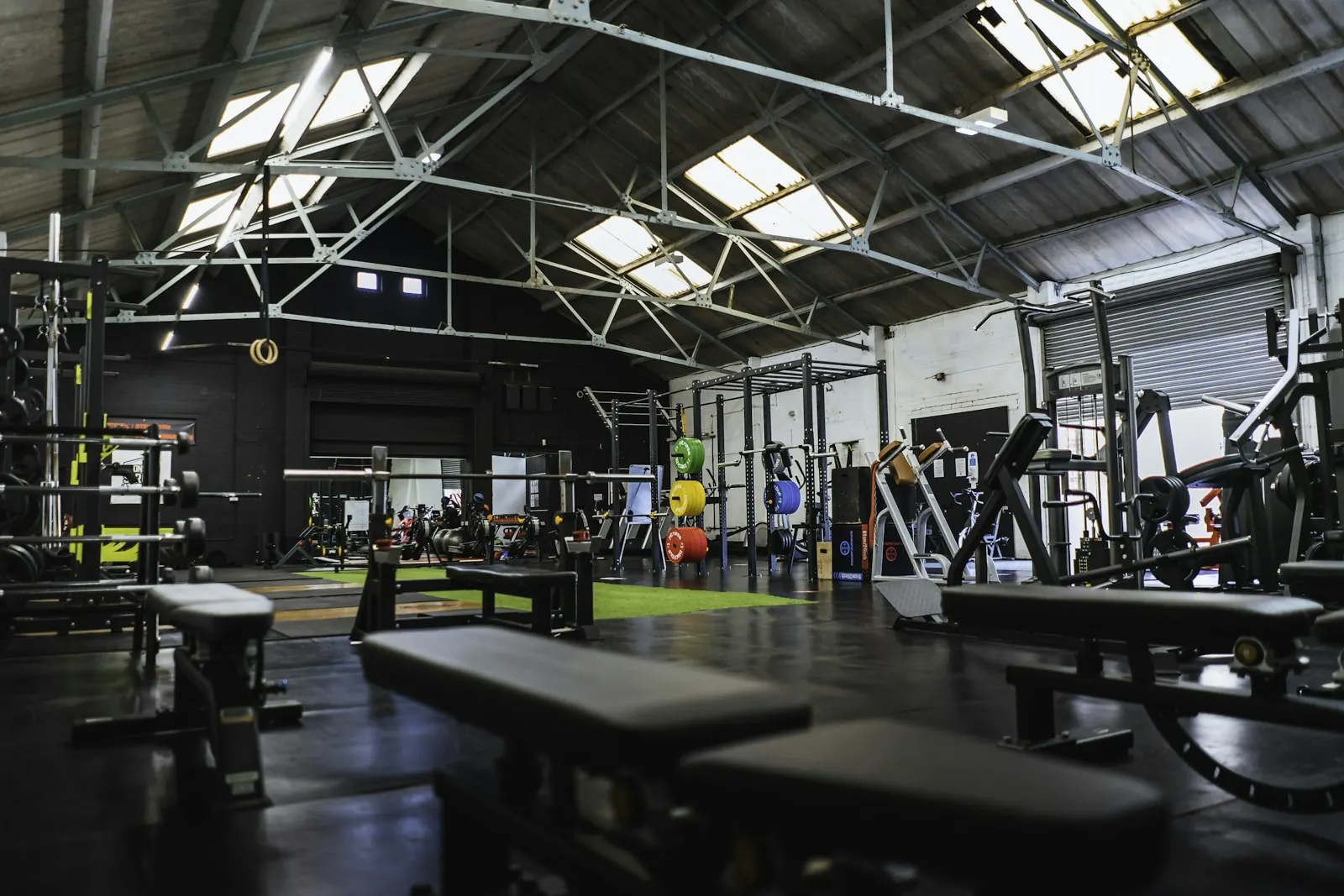 Functional-Bereich in einer Industriehalle mit Trainingsbänken und Rigs